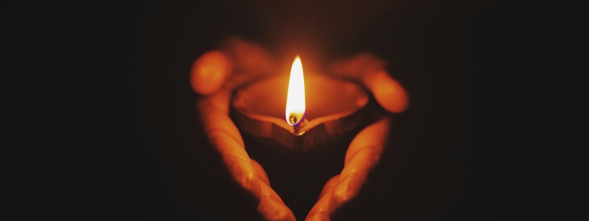 Manos sosteniendo una vela encendida como símbolo de reconocimiento, cuidado y acompañamiento terapéutico.