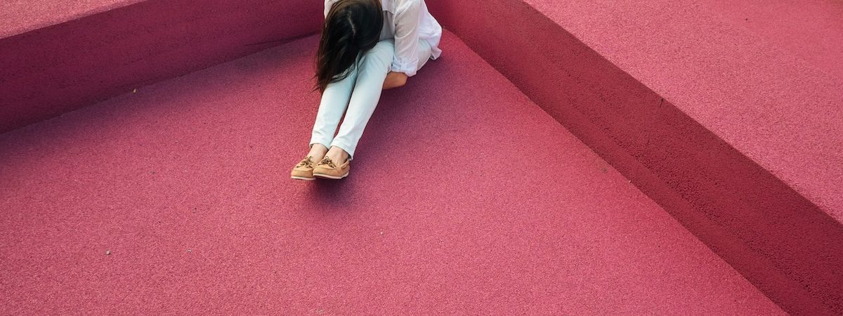 Mujer encogida en un rincón rodeada de muros, como imagen de la culpa y el contexto social.